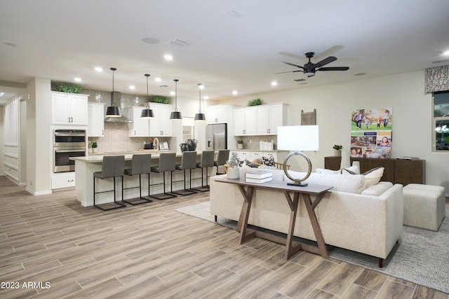 living room featuring ceiling fan, sink, and light hardwood / wood-style floors