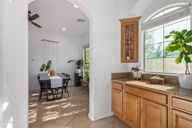 bar featuring ceiling fan, light tile patterned floors, light stone countertops, and a wealth of natural light