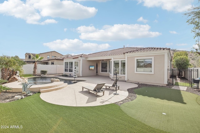 rear view of house with a fenced in pool and a patio