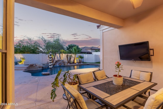 patio terrace at dusk featuring a swimming pool with hot tub