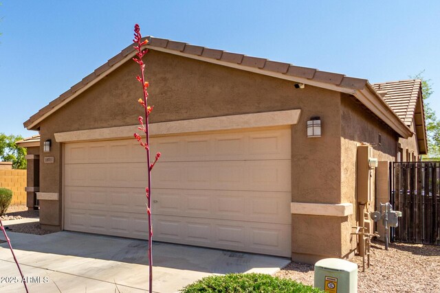 garage with concrete driveway and fence
