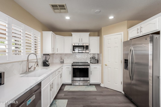 kitchen featuring stainless steel appliances, visible vents, white cabinets, and a sink