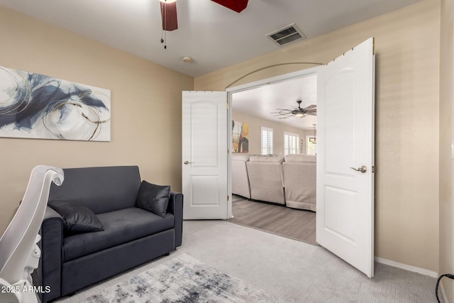 living area featuring visible vents, carpet floors, baseboards, and ceiling fan