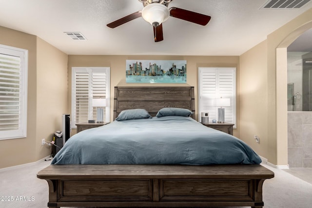 carpeted bedroom featuring arched walkways, visible vents, baseboards, and a ceiling fan