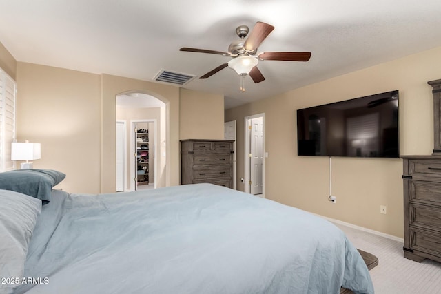 bedroom featuring visible vents, baseboards, arched walkways, ceiling fan, and carpet flooring
