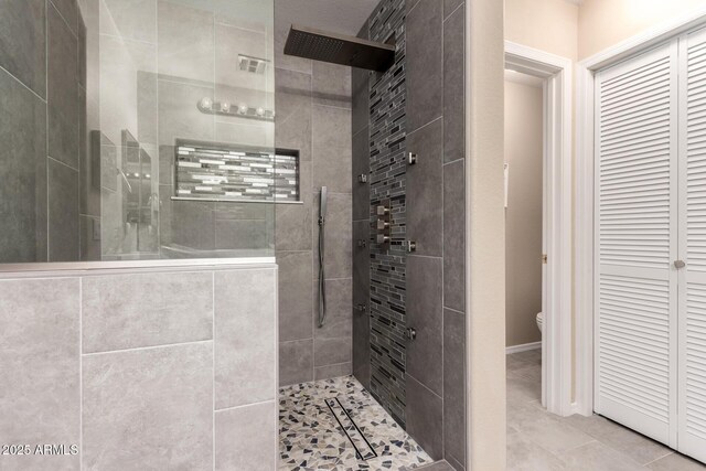 full bathroom with toilet, a closet, and a tile shower