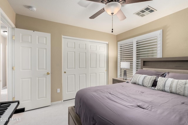 bedroom featuring a closet, visible vents, light colored carpet, and ceiling fan