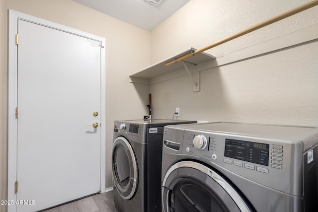 laundry room with visible vents, washing machine and clothes dryer, wood finished floors, and laundry area
