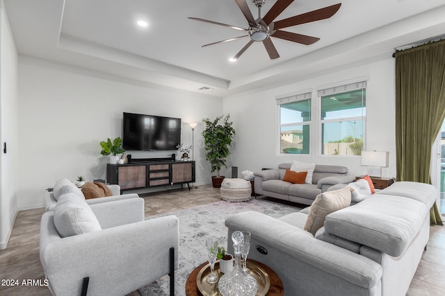 living room with ceiling fan and a raised ceiling