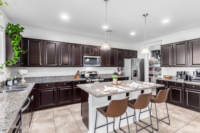 kitchen with appliances with stainless steel finishes, a kitchen breakfast bar, dark brown cabinets, decorative light fixtures, and sink