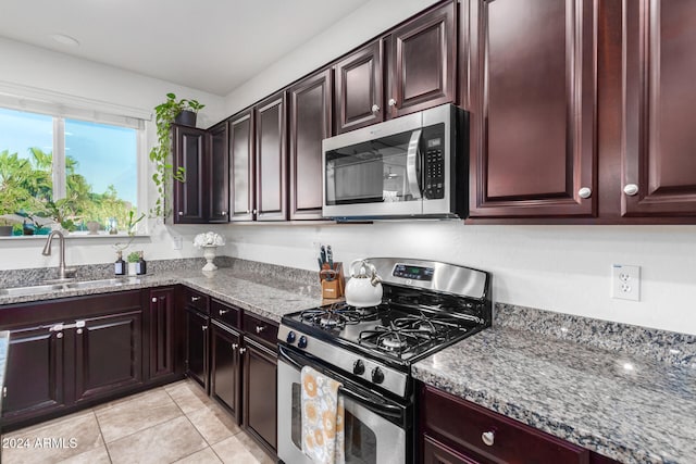 kitchen with light tile patterned floors, stainless steel appliances, sink, and stone countertops