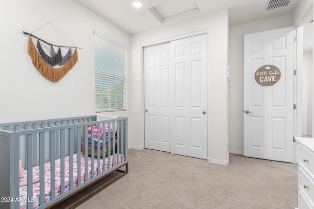 carpeted bedroom featuring a nursery area and a closet