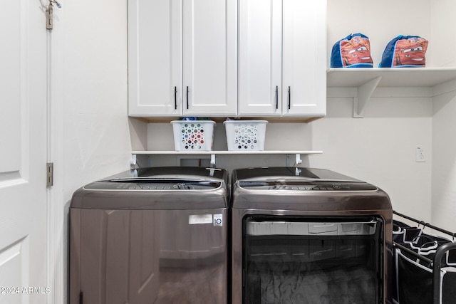 washroom with cabinets and washing machine and clothes dryer