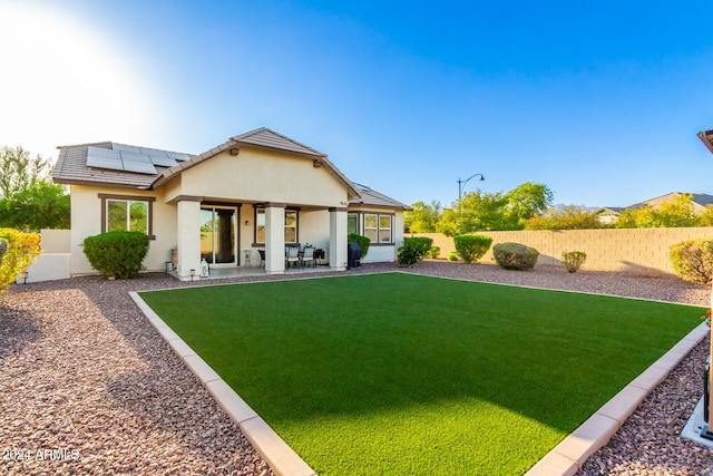 rear view of property featuring solar panels, a yard, and a patio area