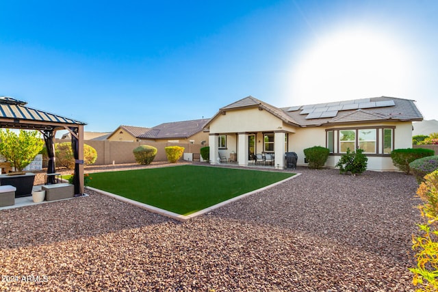 rear view of house featuring solar panels, a jacuzzi, and a patio