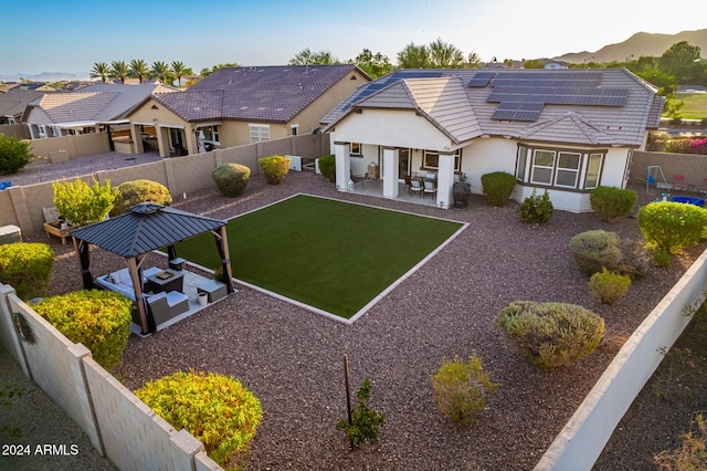 back of property with a patio, solar panels, and a mountain view