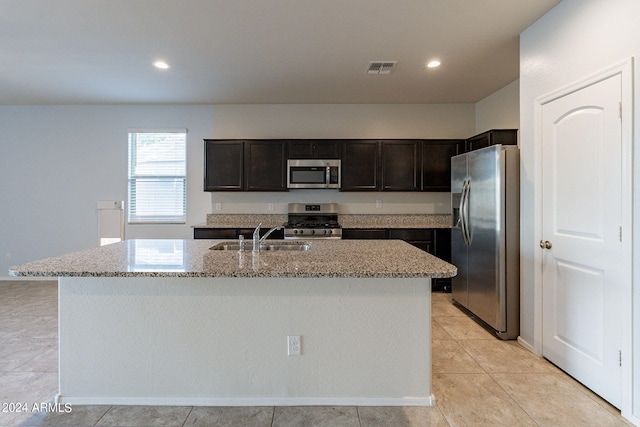 kitchen featuring light stone counters, a kitchen island with sink, appliances with stainless steel finishes, and sink