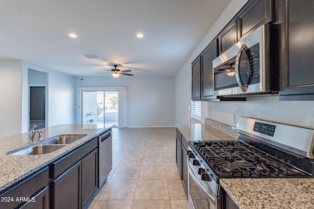 kitchen with light stone countertops, dark brown cabinetry, stainless steel appliances, sink, and light tile patterned floors