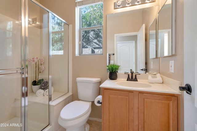 bathroom with vanity, toilet, and a shower with door