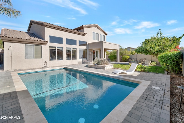 rear view of property featuring a fenced in pool and a patio