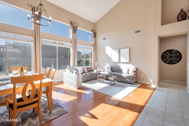 living room with a notable chandelier, light hardwood / wood-style floors, and high vaulted ceiling