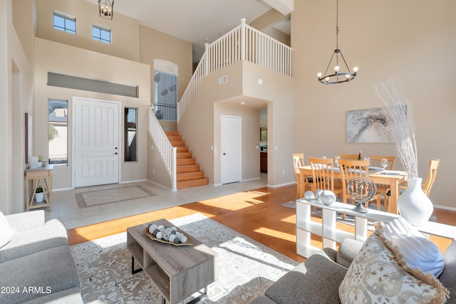 living room with light hardwood / wood-style floors, a high ceiling, and an inviting chandelier