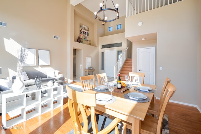 dining space featuring a high ceiling, an inviting chandelier, and light hardwood / wood-style flooring