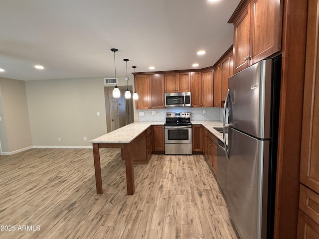 5525 E Thomas Rd Unit C2, Phoenix, AZ 85018 - kitchen featuring stainless steel appliances, a peninsula, light wood-type flooring, decorative backsplash, and brown cabinets
