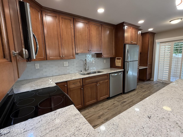 5525 E Thomas Rd Unit C2, Phoenix, AZ 85018 - kitchen featuring appliances with stainless steel finishes, light wood-style flooring, light stone countertops, backsplash, and brown cabinets