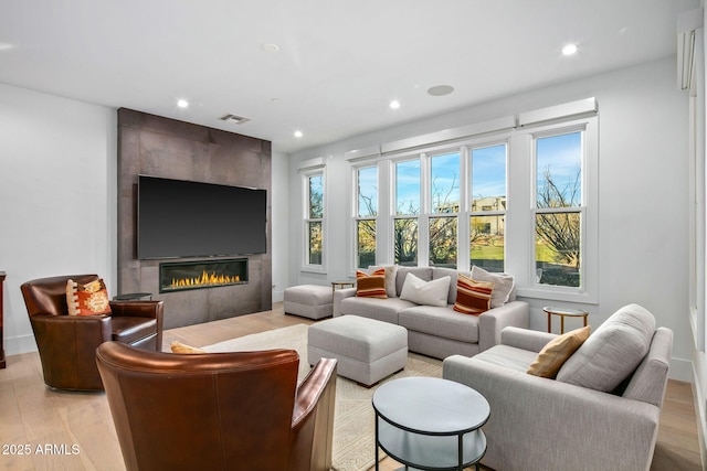 living room featuring a large fireplace and light wood-type flooring