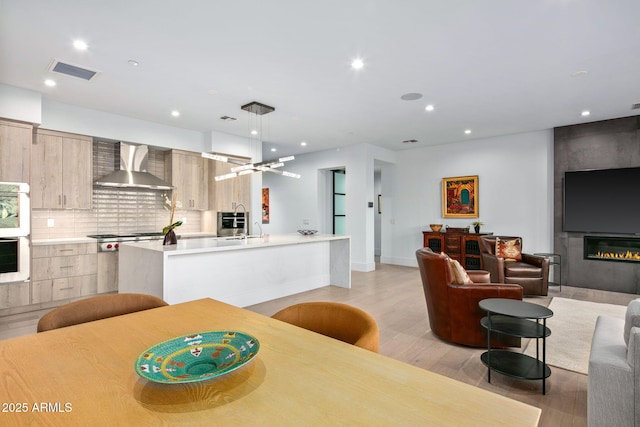 dining space with sink, a fireplace, and light hardwood / wood-style flooring