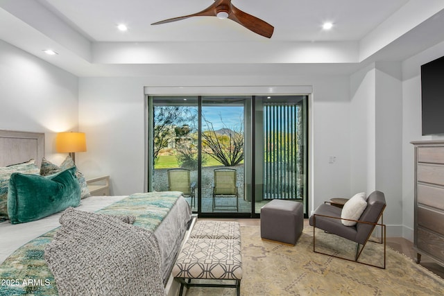 bedroom with wood-type flooring, access to exterior, ceiling fan, and a tray ceiling