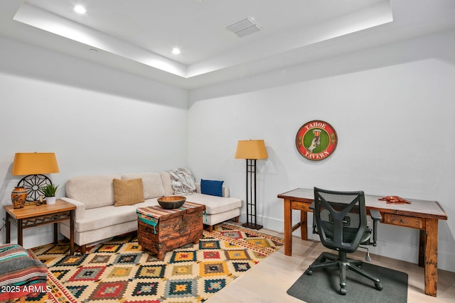 office featuring hardwood / wood-style flooring and a tray ceiling