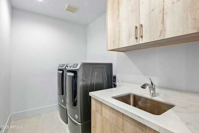 laundry room featuring independent washer and dryer, cabinets, sink, and light tile patterned floors