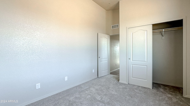 unfurnished bedroom with light carpet and a closet