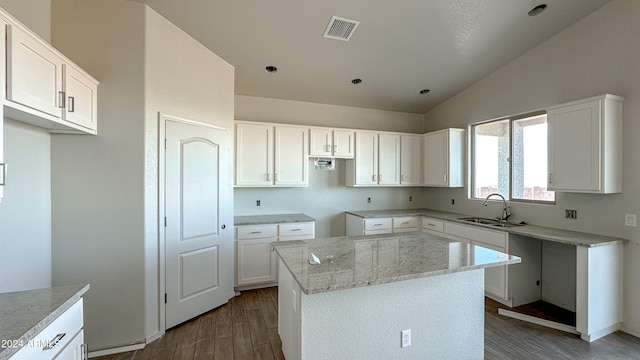 kitchen with a kitchen island, lofted ceiling, sink, and white cabinetry