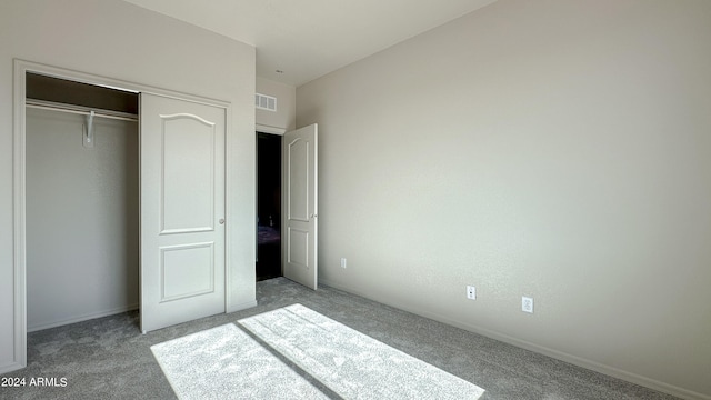 unfurnished bedroom with light colored carpet and a closet