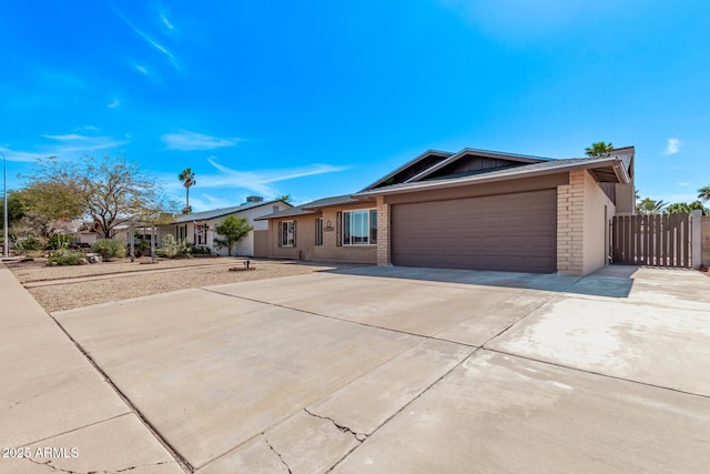 ranch-style house featuring an attached garage, concrete driveway, and fence