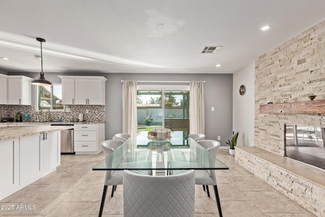 dining room with a stone fireplace, plenty of natural light, recessed lighting, and visible vents