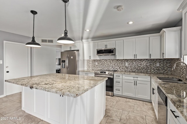 kitchen featuring visible vents, a sink, a kitchen island, stainless steel appliances, and decorative backsplash