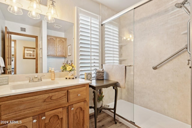 bathroom with hardwood / wood-style floors, vanity, and an enclosed shower