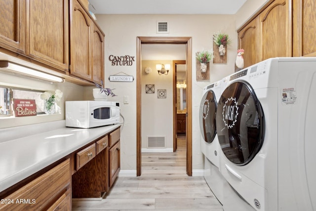 laundry room featuring cabinets, light wood-type flooring, and washing machine and clothes dryer