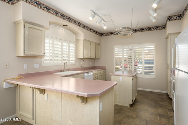 kitchen featuring sink, a kitchen breakfast bar, fridge, kitchen peninsula, and cream cabinets