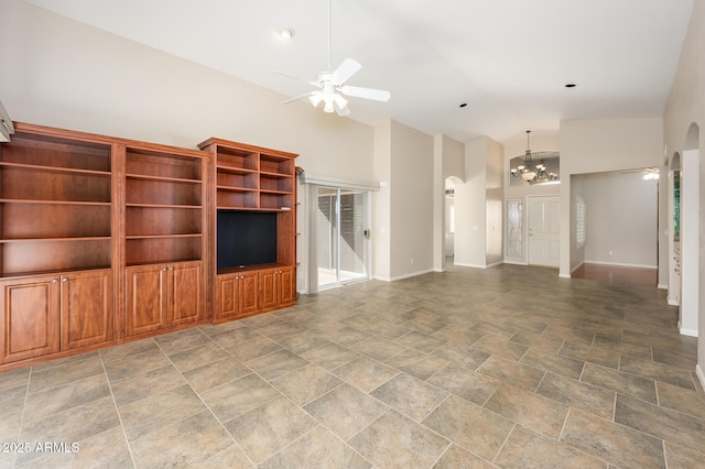 unfurnished living room with high vaulted ceiling and ceiling fan with notable chandelier