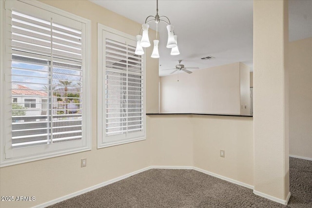 carpeted spare room featuring visible vents, baseboards, and ceiling fan with notable chandelier