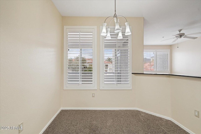 carpeted empty room with ceiling fan with notable chandelier and baseboards