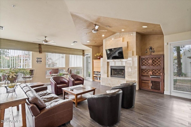 living room with dark wood finished floors, a tiled fireplace, ceiling fan, and vaulted ceiling