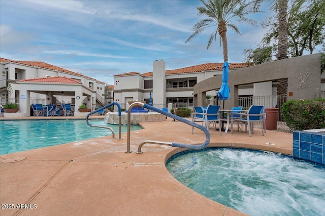 pool with a patio, a community hot tub, and fence