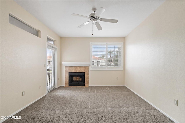 unfurnished living room with a tile fireplace, baseboards, a ceiling fan, and carpet floors