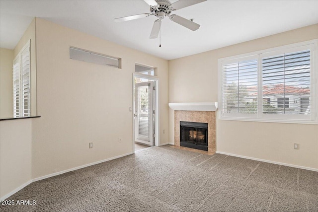 unfurnished living room featuring baseboards, carpet floors, a ceiling fan, and a tiled fireplace